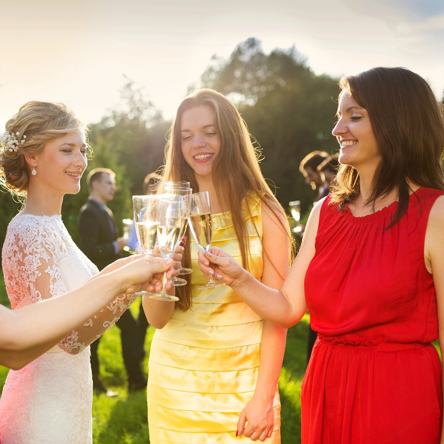 Noiva e convidadas brindam num casamento ao ar livre.