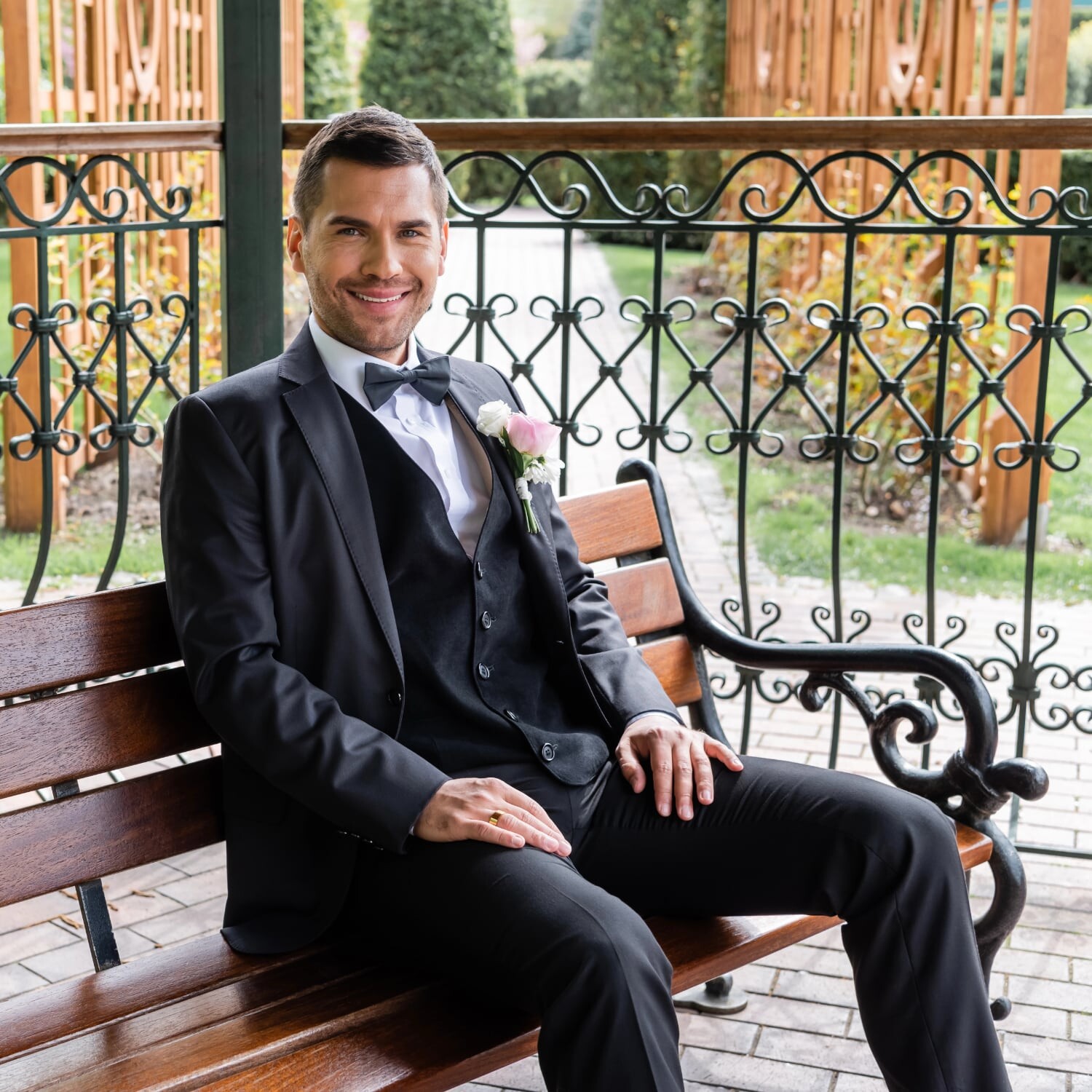 Noivo sentado num banco de jardim no dia do casamento.