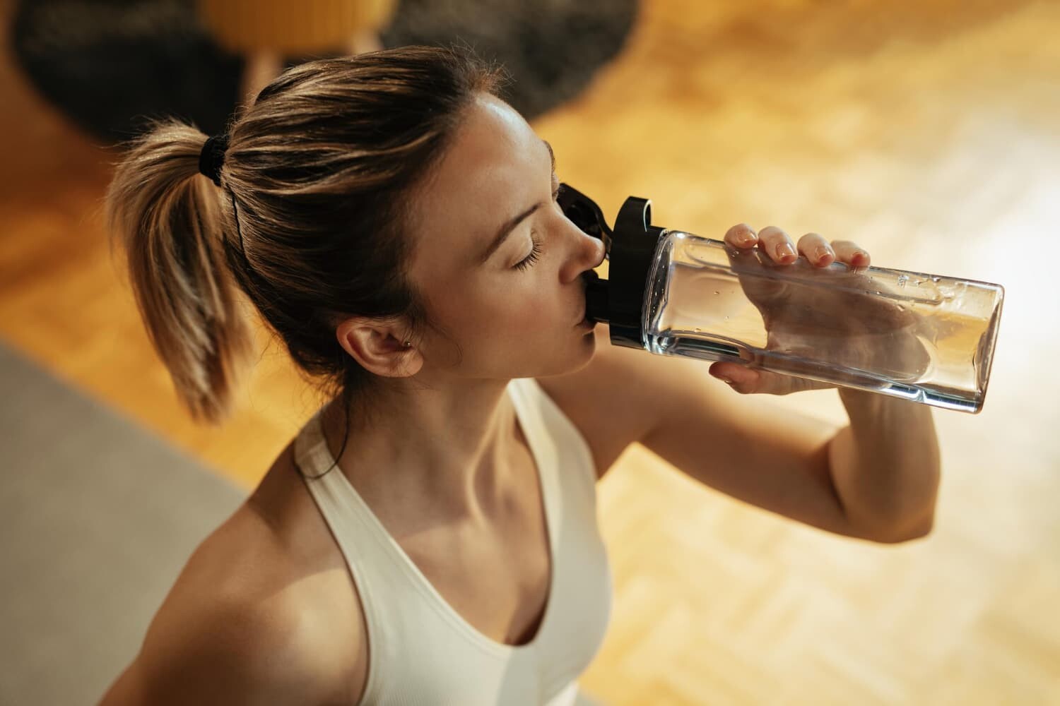 Mulher no ginásio a beber água.